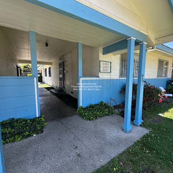a blue house with a sign that says "for sale" on the front porch.