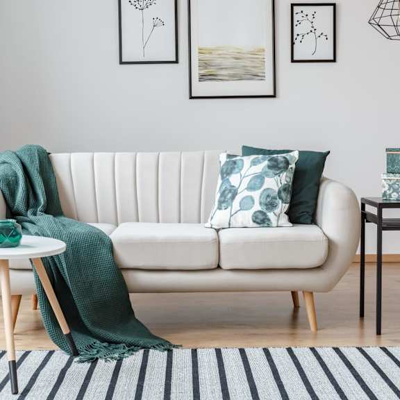 A living room with a white sofa, a small table, and a plant.