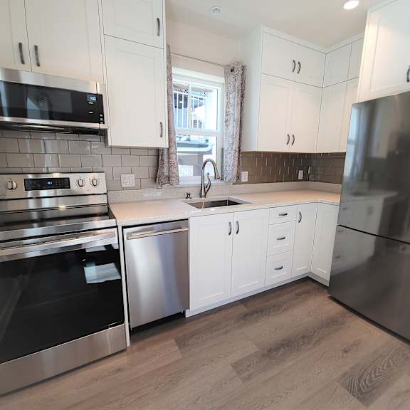 a kitchen with white cabinets and stainless steel appliances.