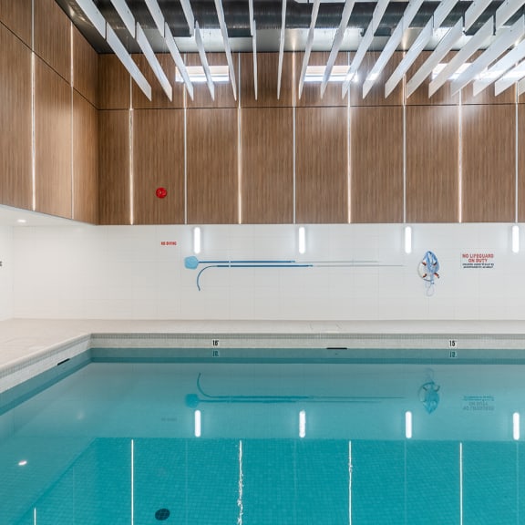 a large indoor swimming pool with white walls and wood paneling