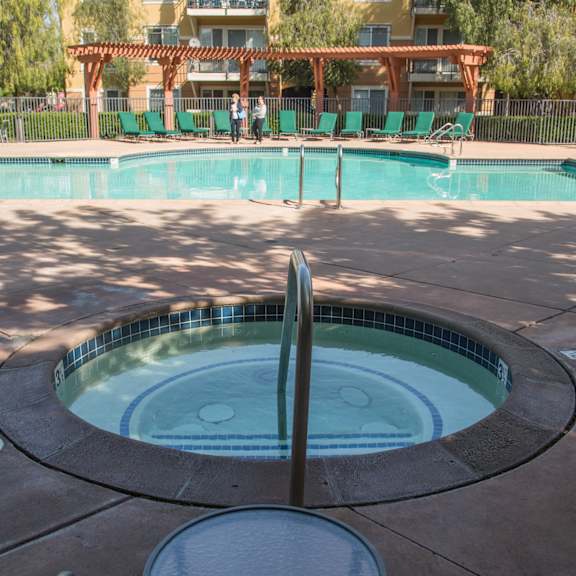 a large swimming pool with a table and chairs in front of a building