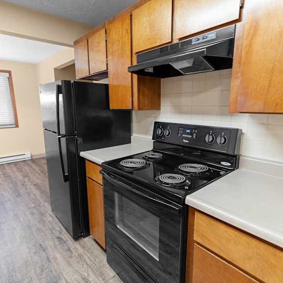 a black refrigerator and stove in a kitchen with wooden cabinets.