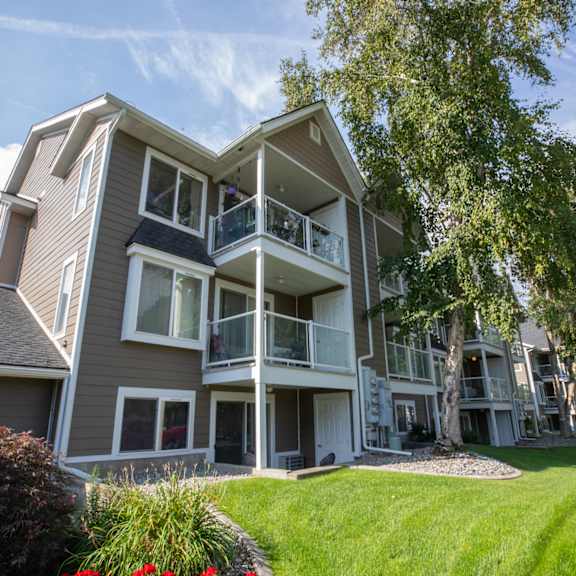 a large apartment building with a balcony and a tree in front.