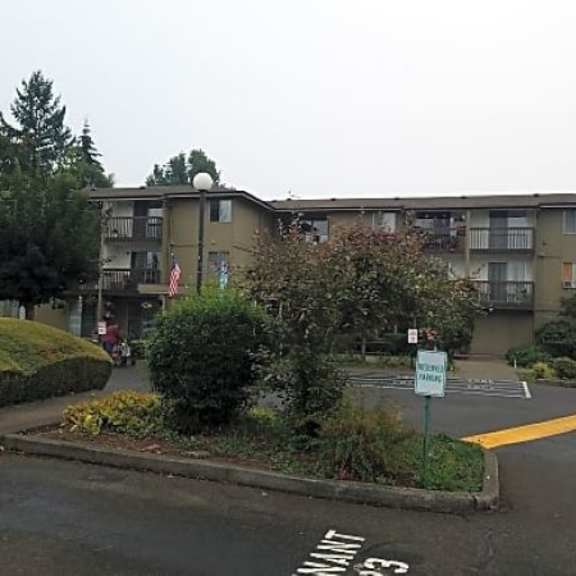 a parking lot with an apartment building in the background