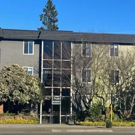a building with a glass front door and trees in front of it