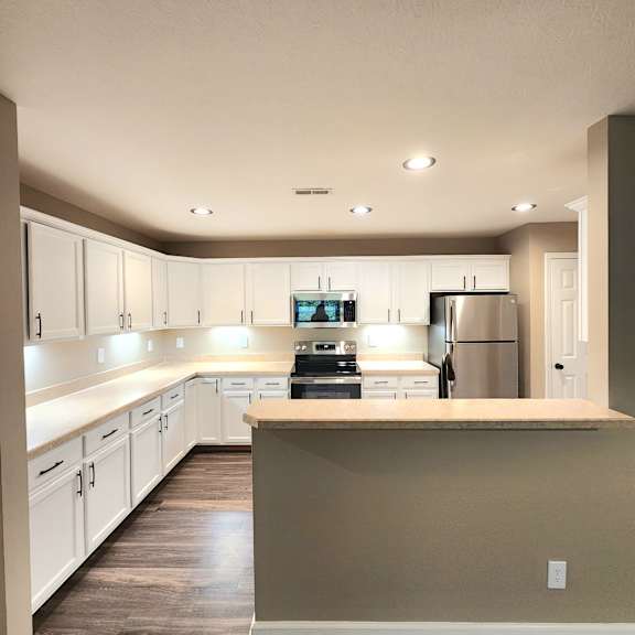 A kitchen with white cabinets and a refrigerator.