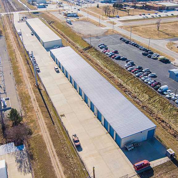an aerial view of a parking lot with a long building and cars parked.