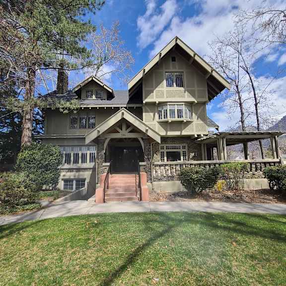 a large house with a triangular roof and a stone wall.