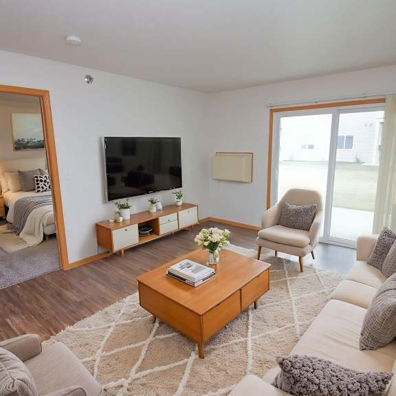 a living room with a large couch, a coffee table, and a flat-screen tv.