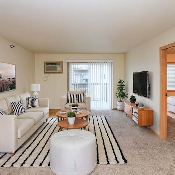 a living room with a white couch, a coffee table, and a tv.