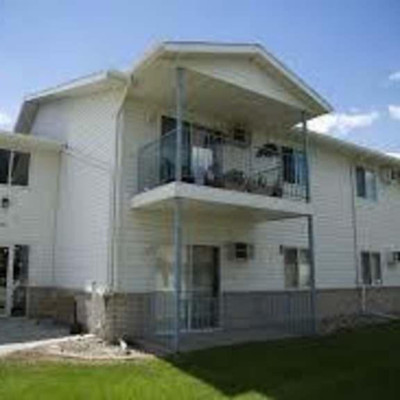 a white two-story apartment building with balconies on the second floor.