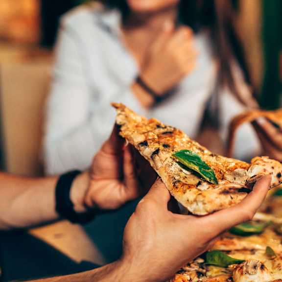 A person is making a quesadilla with cheese and green toppings.