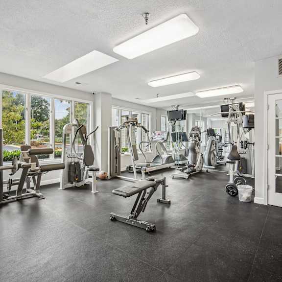 A spacious gym with a variety of equipment and a view of the outdoors through the windows.