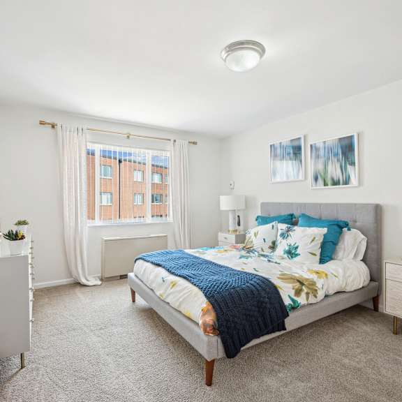 A bedroom with a bed, nightstand, and window.