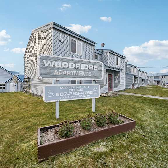 a sign for woodridge apartments stands in front of the building.