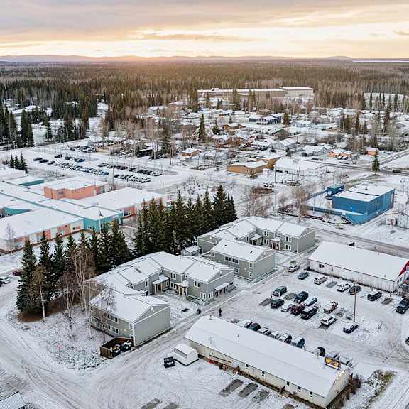 a small town with buildings and cars is surrounded by snow.