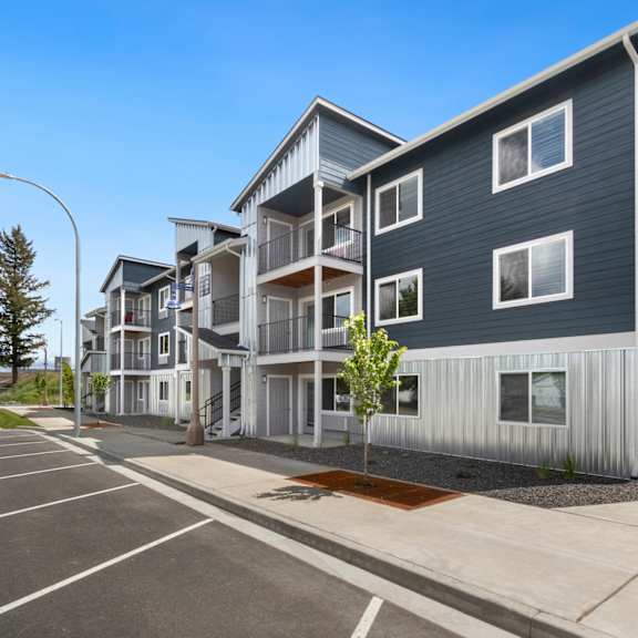 a modern apartment complex with a parking lot in front.