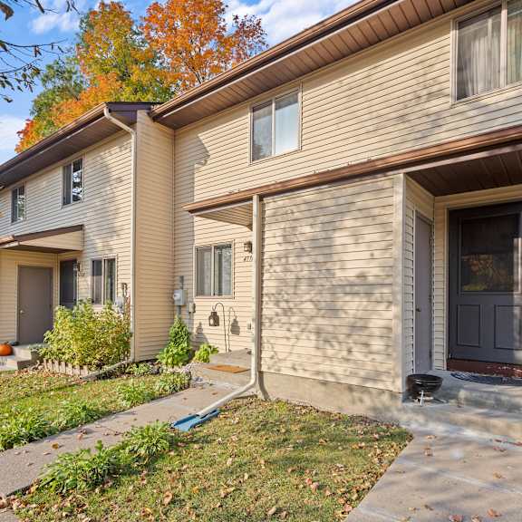 a beige house with a brown door and a small front yard.