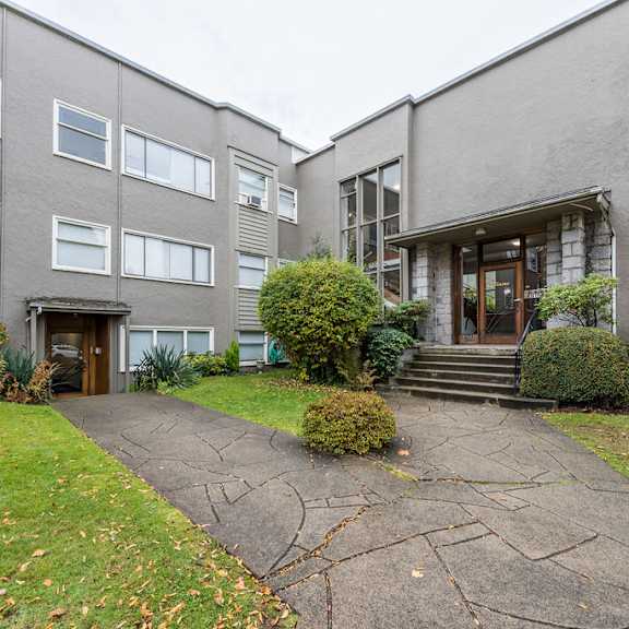 a view of the front of a grey building with a walkway in front of it
