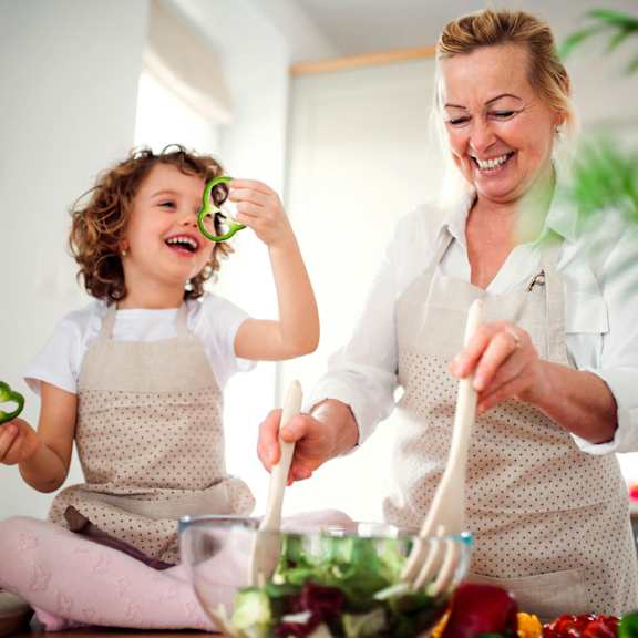 A woman and a child are preparing food together in a kitchen.