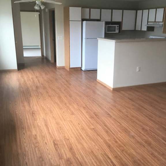 a kitchen with white cabinets and a wooden floor.