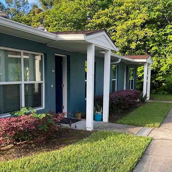 a blue house with white columns and a porch.
