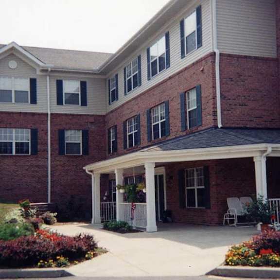 a red brick building with a white porch and a white picket fence.