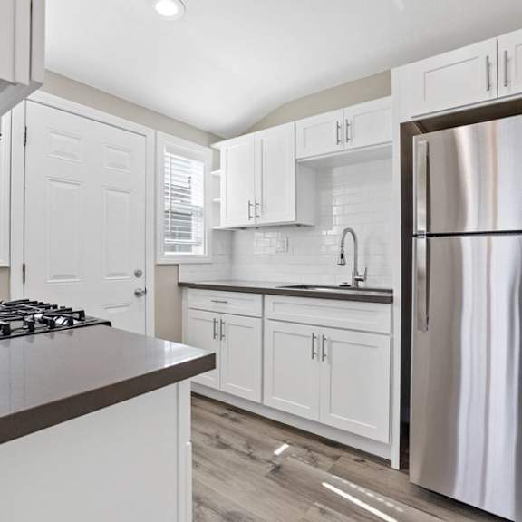 a kitchen with white cabinets and a stainless steel refrigerator at huntington manor homes apartment, california