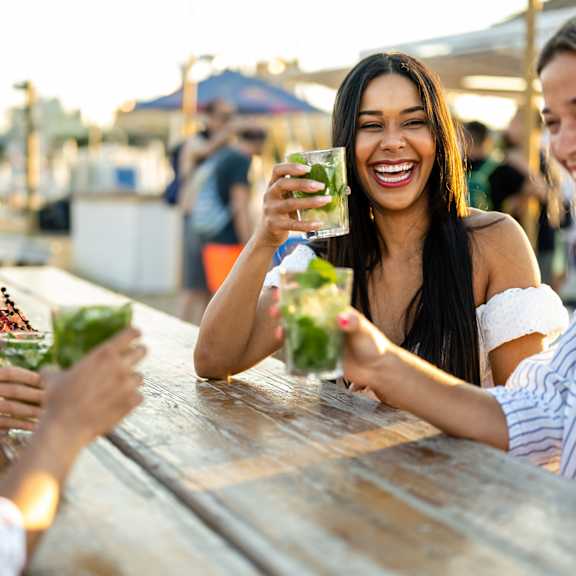 four people are sitting at a table, laughing and enjoying drinks at 325 on seventeenth apartments, costa mesa, ca, 92627