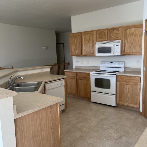 an empty kitchen with white appliances and wooden cabinets
