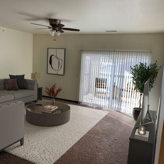 a living room with a ceiling fan and a sliding glass door