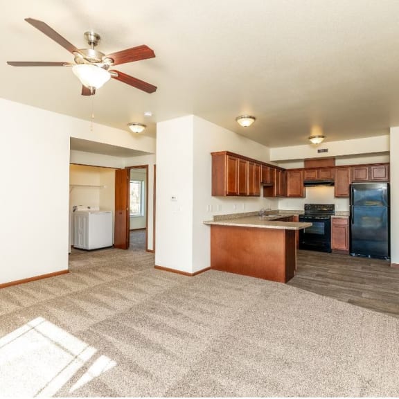 a living room with a kitchen and a ceiling fan