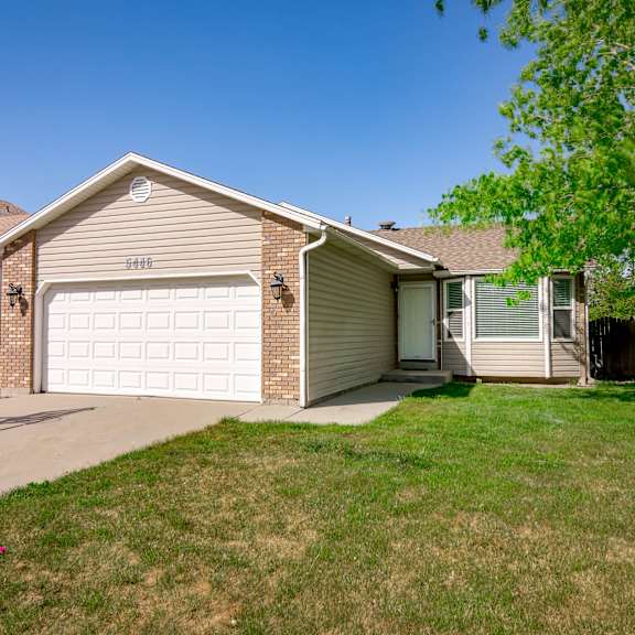 a house with a white garage door is surrounded by a green lawn.