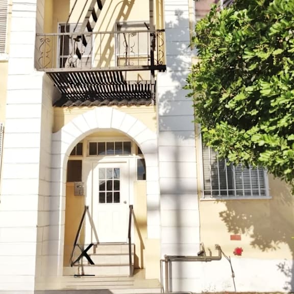 the front of a building with a white door and a balcony
