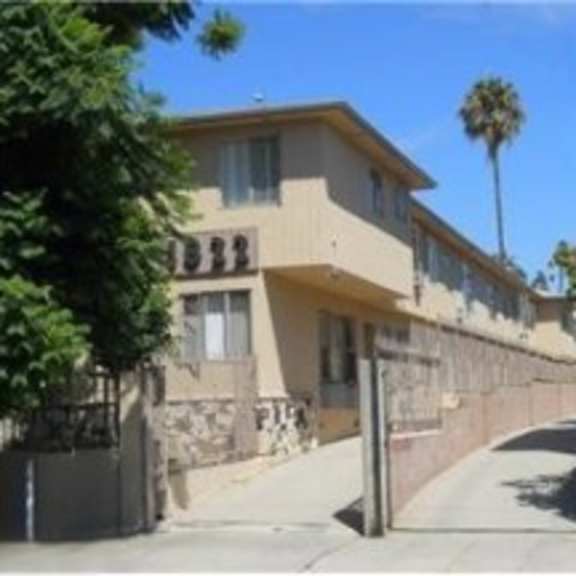 a building with a fence and a palm tree