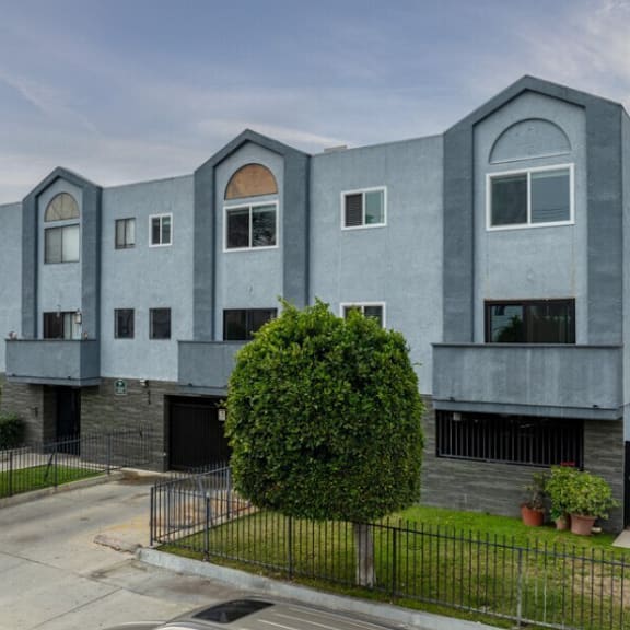 a blue and gray building with a yard and a fence