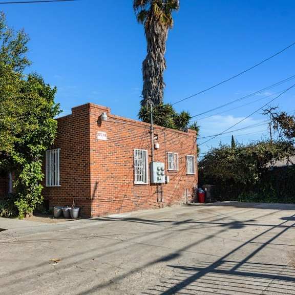 an old brick building on a street with a palm tree