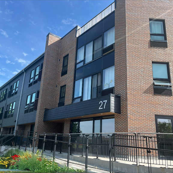 a brick apartment building with a black railing and a gate