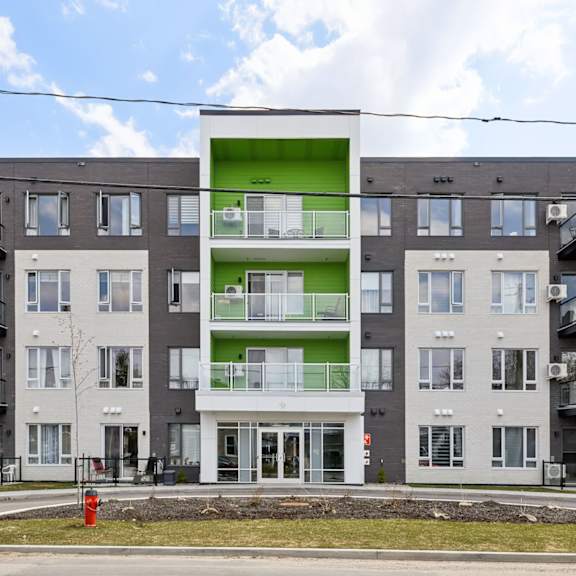 a large apartment building with a green and white section in the middle.