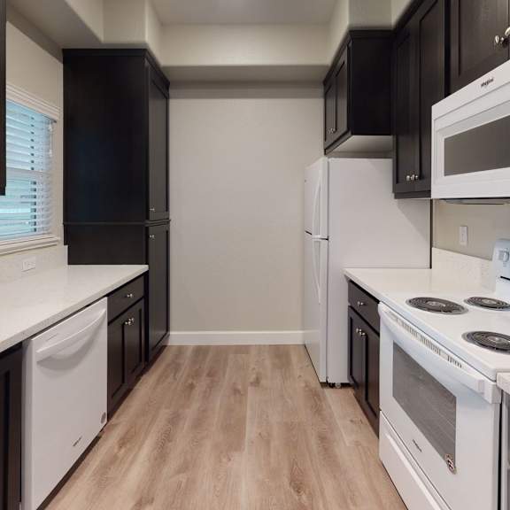 a kitchen with white appliances and black cabinets at heritage landing apartments, chico, ca
