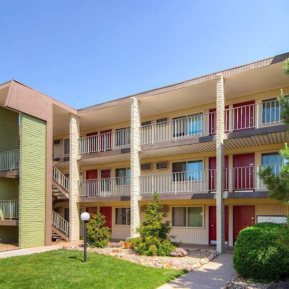 a multi-story apartment building with a green lawn in front.