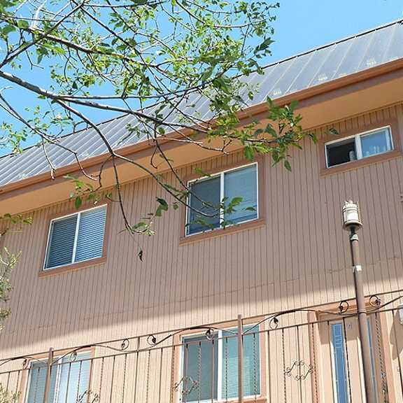 a building with a corrugated metal roof and a tree branch in the foreground.