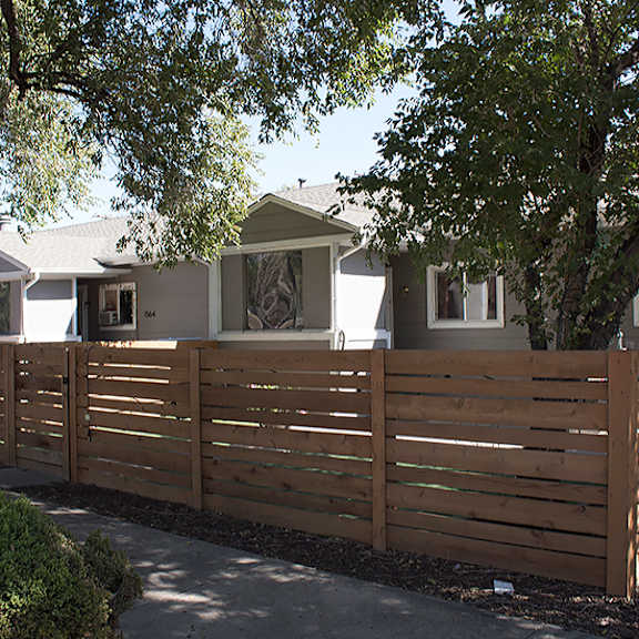 a wooden fence separates a row of houses.