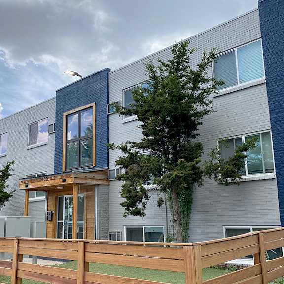 a modern two-story house with a wooden fence in front.