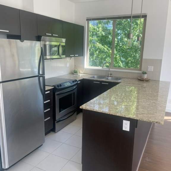 a kitchen with a refrigerator, oven, and sink.