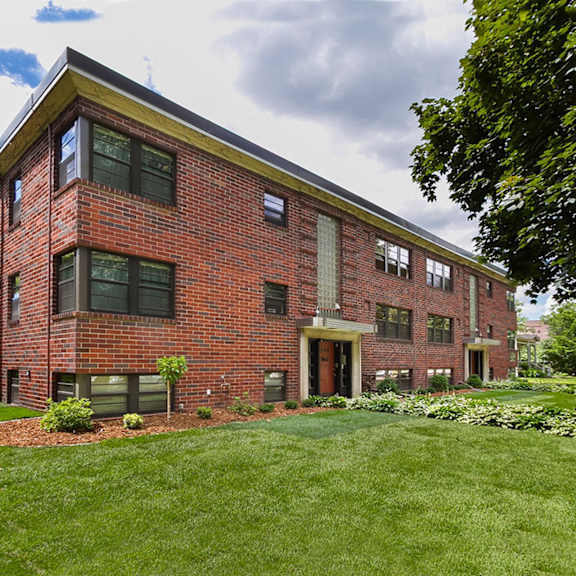 a red brick building with a green lawn in front.