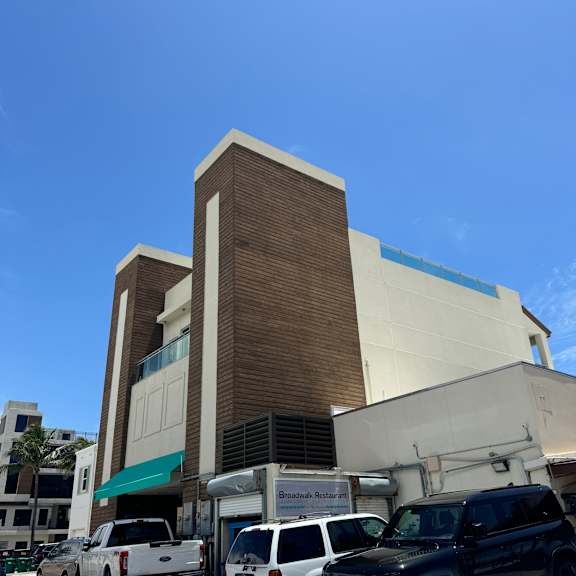 a black suv is parked in front of a building with a white truck and a white van.