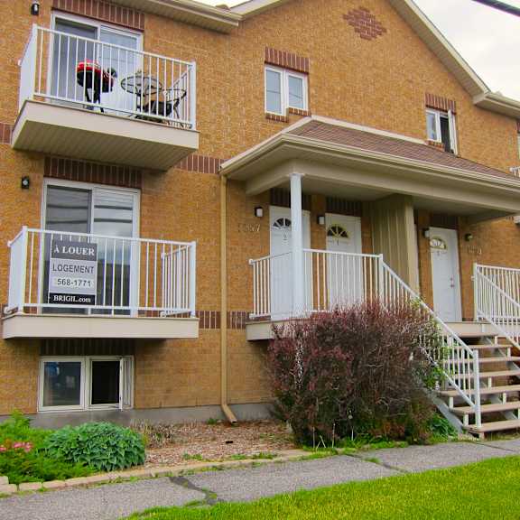 a brick apartment building with a balcony and stairs leading to the front door.