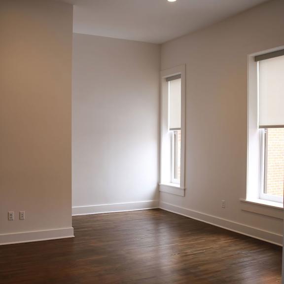 a room with wooden floors and two windows.