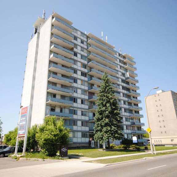 a tall residential building with a parking lot in front.